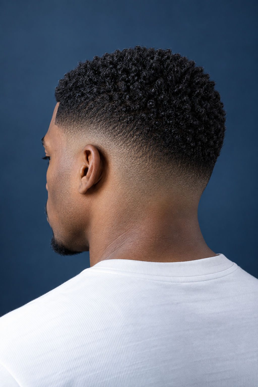 Rear view of an adult Black model with short textured curls and a clean low fade